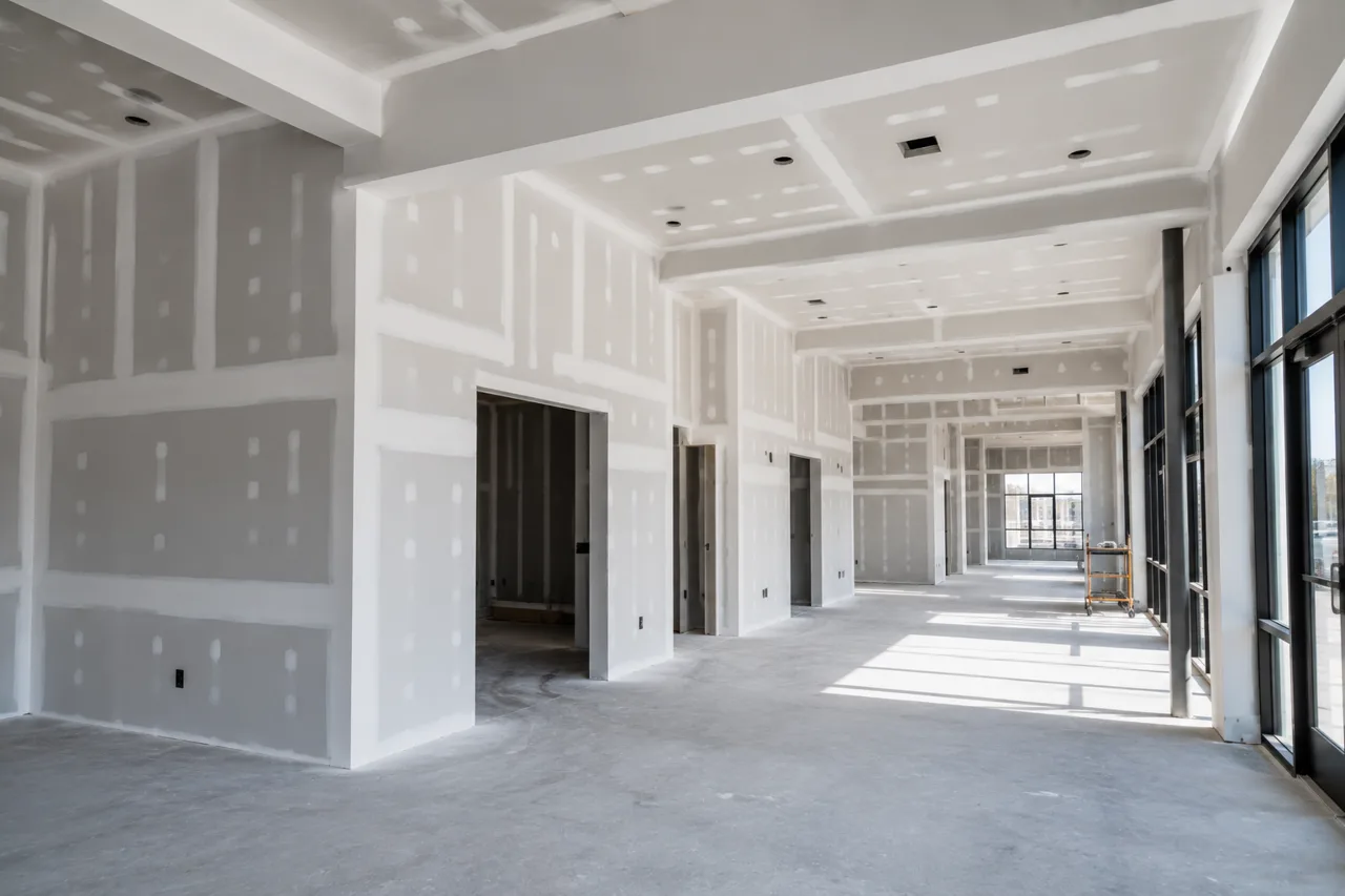 Completed commercial build-out with taped and finished drywall walls, framed door openings and a finished ceiling along a window wall